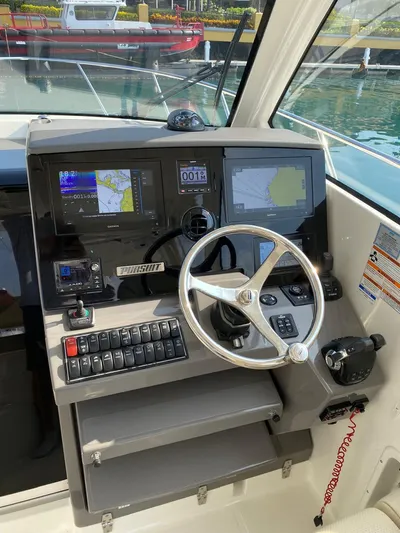 Recovery Room Yacht Photos Pics 2020 Pursuit OS 325 Offshore boat dashboard with navigation screens and steering wheel.