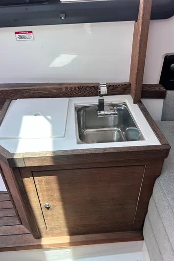  Yacht Photos Pics 2019 Axopar 37 Sun Top boat kitchenette with sink and wooden cabinetry.