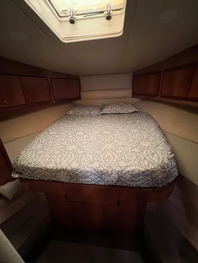 Play Pen Yacht Photos Pics 2001 Bertram 510 Convertible cabin with bed, wooden cabinets, and overhead hatch.