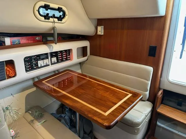  Yacht Photos Pics 2003 Pursuit 3070 Express cabin with wood table and beige seating.