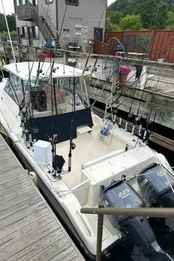  Yacht Photos Pics 2003 Pursuit 3070 Express boat docked, equipped with fishing rods and twin 225 horsepower engines.