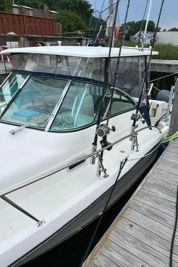  Yacht Photos Pics 2003 Pursuit 3070 Express boat docked, featuring fishing rods and a sleek design.