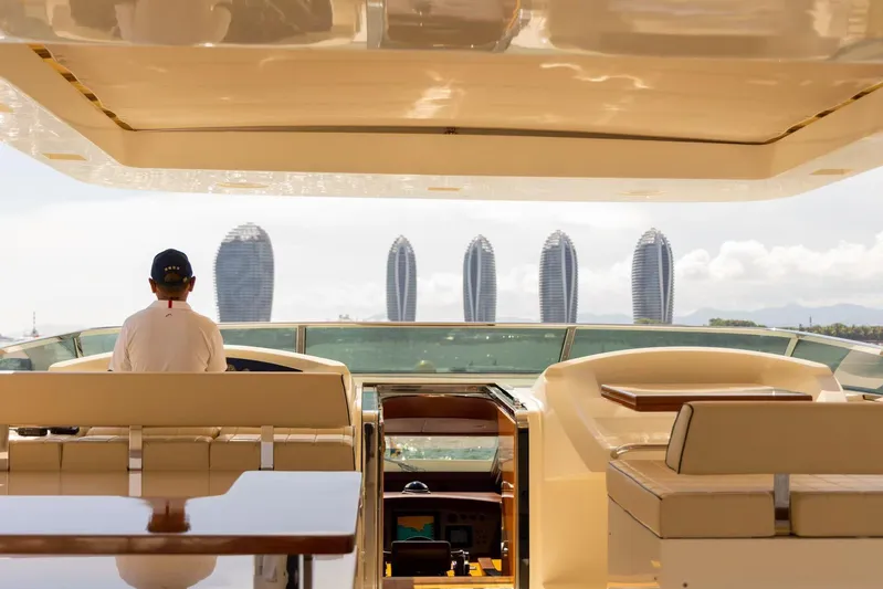  Yacht Photos Pics Person steering 2010 Azimut 105 yacht with modern cityscape in background.