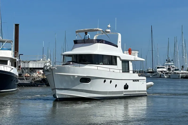 Smooth Yacht Photos Pics 2019 Beneteau Swift Trawler 50 navigating marina, surrounded by sailboats under clear blue sky.