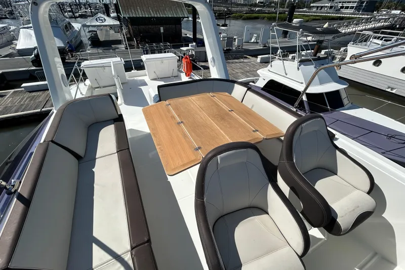 Smooth Yacht Photos Pics 2019 Beneteau Swift Trawler 50 flybridge with seating and wooden table at marina.
