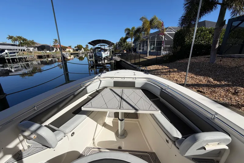  Yacht Photos Pics 2016 Cobia 344 Center Console boat docked by waterfront homes, featuring spacious seating and table.
