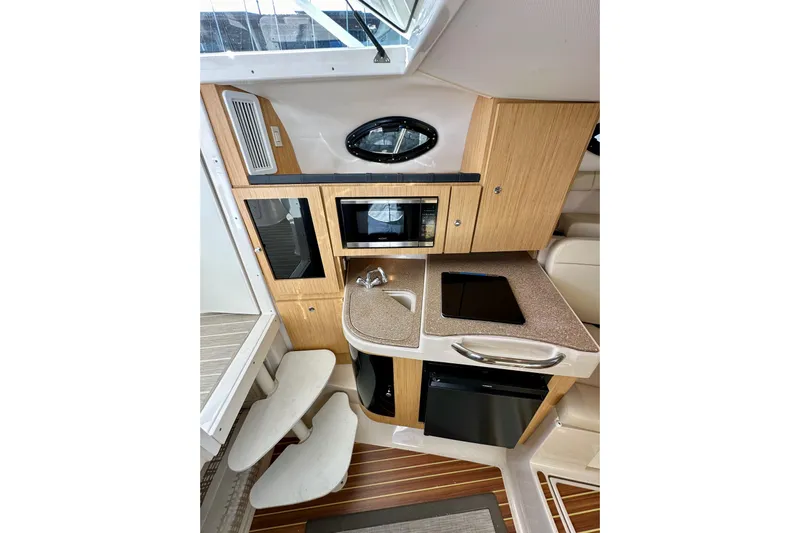 Seahorse Yacht Photos Pics 2018 Wellcraft 290 Coastal boat interior with kitchenette, featuring wood cabinetry and modern appliances.