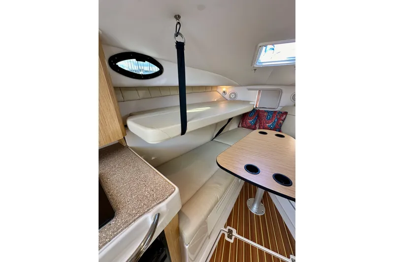 Seahorse Yacht Photos Pics 2018 Wellcraft 290 Coastal cabin interior with seating, table, and porthole window.