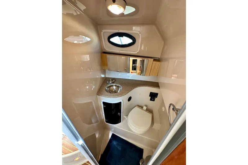 Seahorse Yacht Photos Pics 2018 Wellcraft 290 Coastal boat bathroom with sink, toilet, and porthole window.