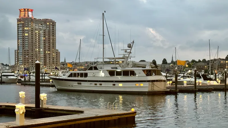 Adventurer Yacht Photos Pics Luxury yacht "Burger 86 Raised Pilothouse" docked at marina, cityscape in background, evening setting.