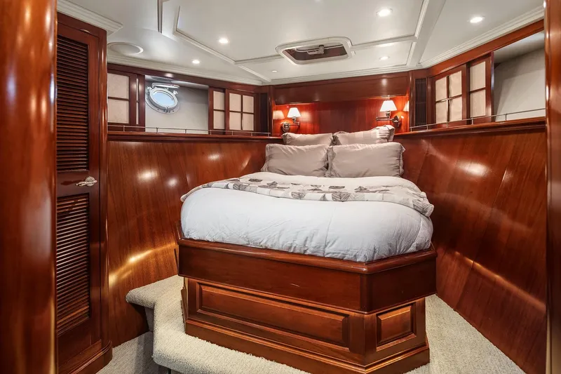 Jade Panama Yacht Photos Pics Luxurious wood-paneled bedroom in 2001 Rayburn Flush Deck yacht, featuring cozy bedding and elegant lighting.