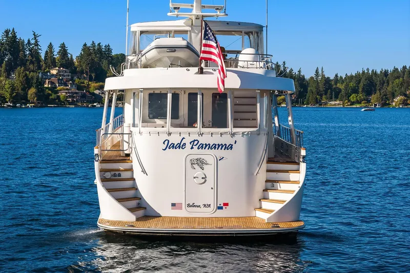 Jade Panama Yacht Photos Pics Rayburn Flush Deck 2001 yacht on serene lake with American flag, surrounded by trees.