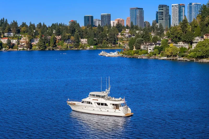 Jade Panama Yacht Photos Pics 2001 Rayburn Flush Deck yacht on a serene lake with city skyline backdrop.