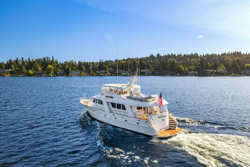 Jade Panama Yacht Photos Pics Luxurious 2001 Rayburn Flush Deck yacht cruising on a serene lake under a clear blue sky.