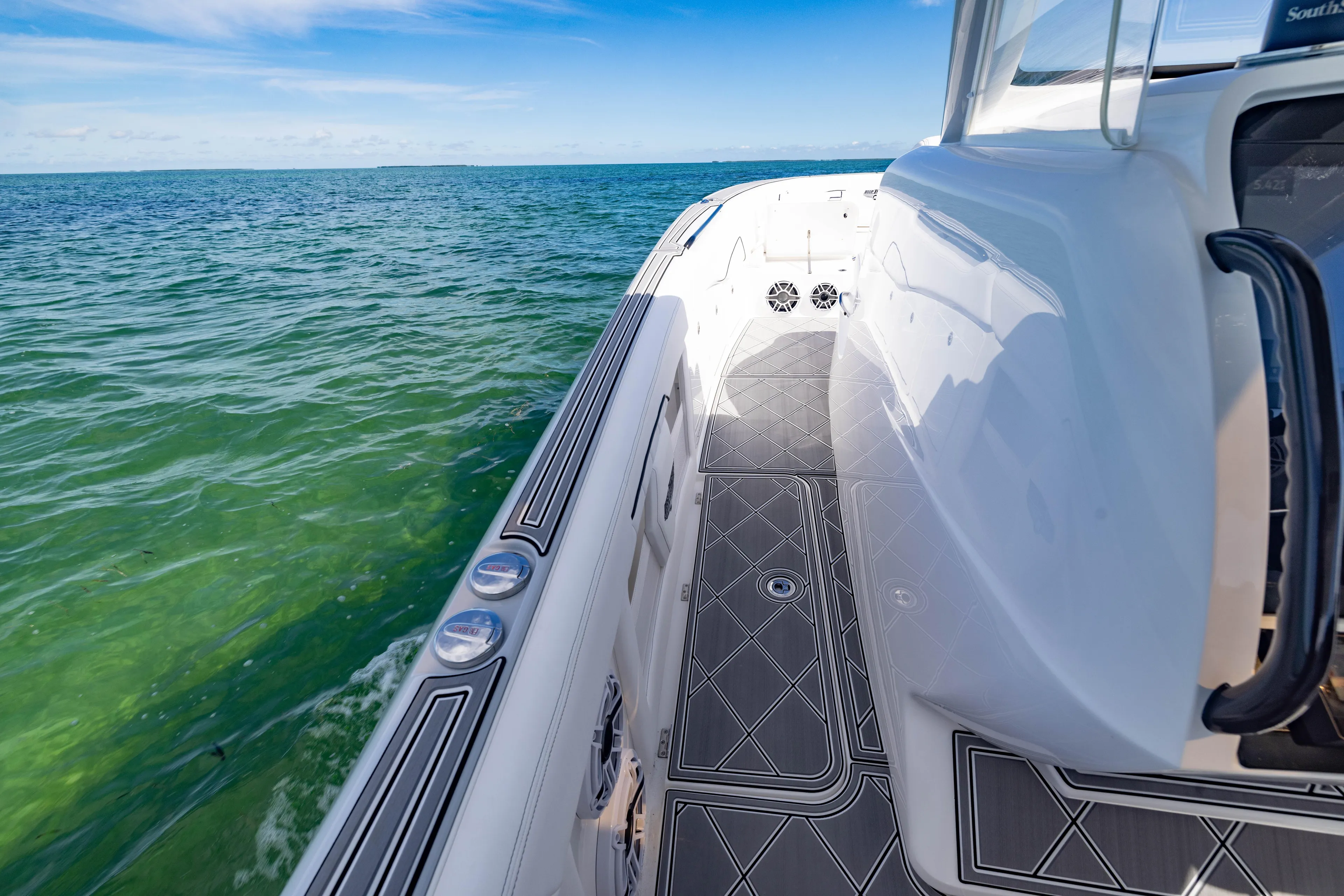  Yacht Photos Pics 2024 Deep Impact 399 Sport boat on clear ocean water, showcasing sleek design and deck details.