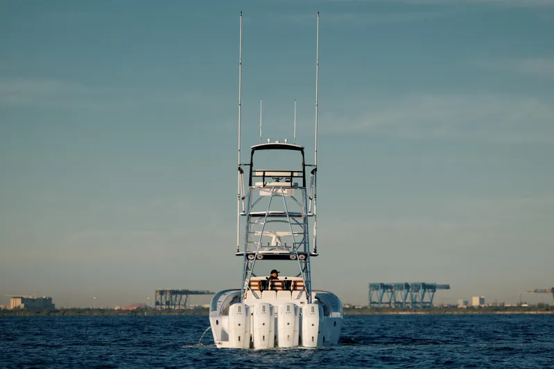  Yacht Photos Pics 2026 Front Runner 47 Center Console boat on calm water, distant industrial backdrop.
