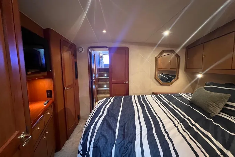 Reel Interest Yacht Photos Pics Luxurious bedroom interior of 2002 Ocean Yachts 56 Super Sport with striped bedding and wood cabinetry.