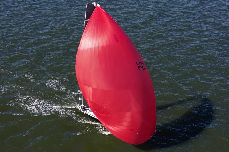Dark Storm Yacht Photos Pics 2019 J Boats J 121 sailing with a large red spinnaker on open water.