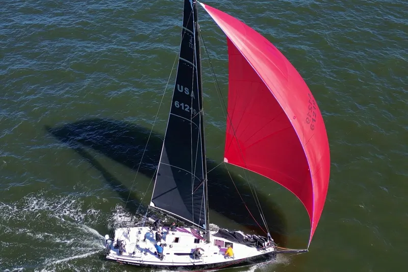Dark Storm Yacht Photos Pics 2019 J Boats J 121 sailing with vibrant red spinnaker on open water.