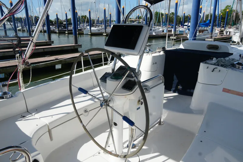 Marabelle Yacht Photos Pics Steering wheel of 2005 Hunter 41 AC sailboat at marina, surrounded by docked boats.