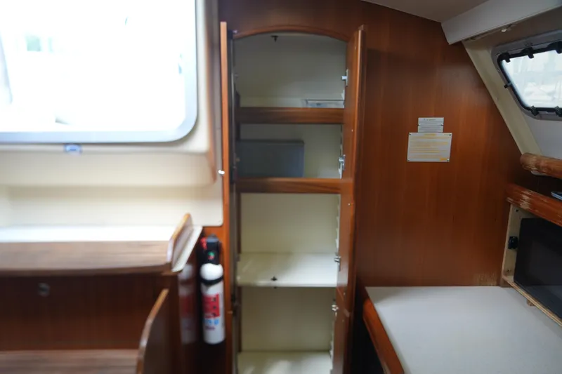 Marabelle Yacht Photos Pics Interior of 2005 Hunter 41 AC sailboat with open wooden cabinet and window.