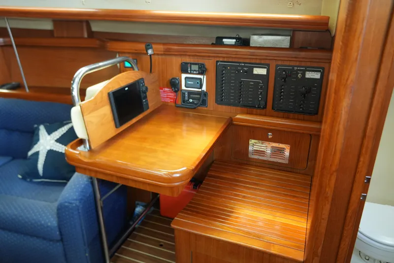 Marabelle Yacht Photos Pics Navigation station in a 2005 Hunter 41 AC sailboat with control panels and seating.