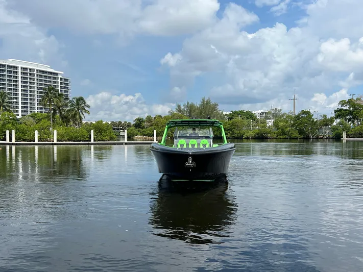  Yacht Photos Pics Midnight Express 2020 boat on calm water, surrounded by lush greenery and buildings.