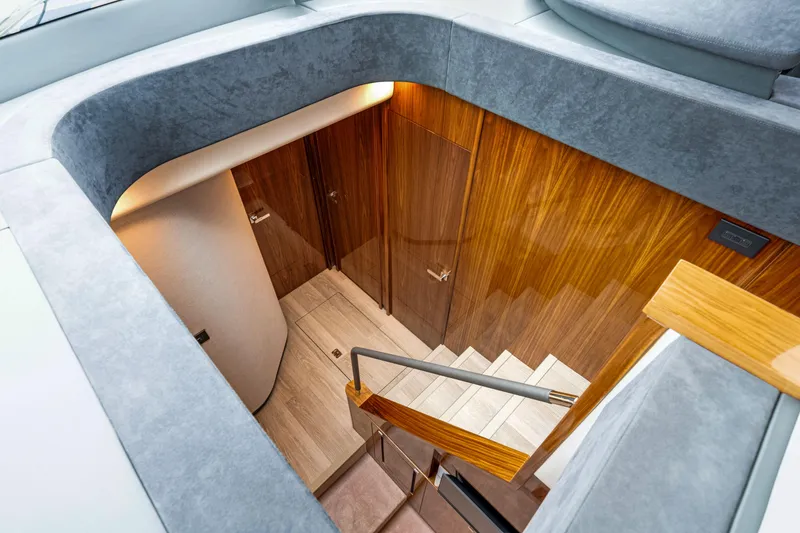  Yacht Photos Pics Interior staircase of 2026 Riviera 6000 Sport Yacht with wooden paneling and modern design.