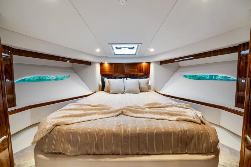  Yacht Photos Pics Luxurious bedroom interior of 2026 Riviera 6000 Sport Yacht with elegant bedding and wood accents.