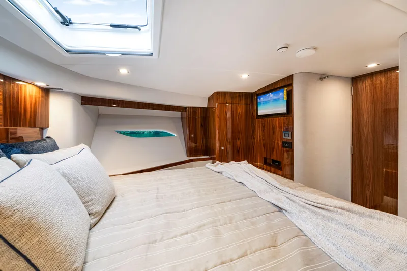  Yacht Photos Pics Luxurious bedroom interior of 2026 Riviera 6000 Sport Yacht with elegant wood finishes.