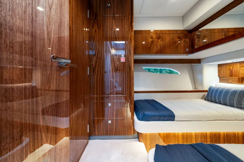  Yacht Photos Pics Luxurious interior of 2026 Riviera 6000 Sport Yacht with elegant wood finishes and cozy bedding.