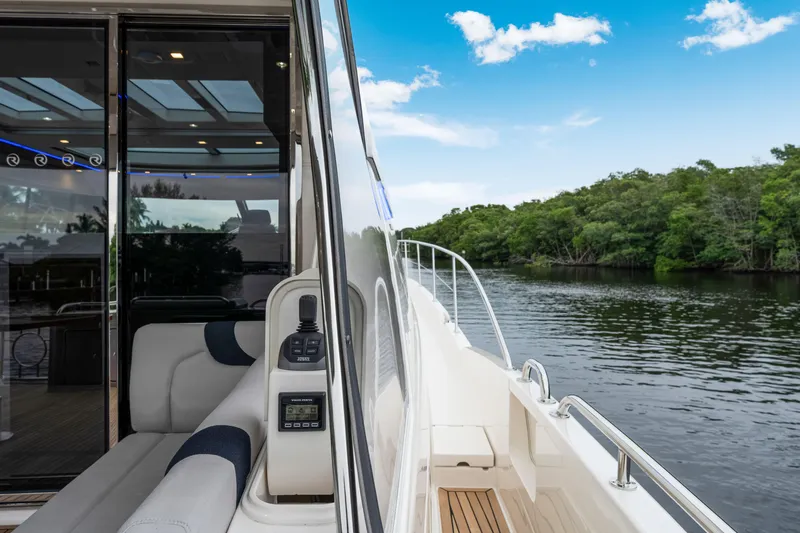  Yacht Photos Pics 2026 Riviera 6000 Sport Yacht cruising on a serene river with lush greenery.