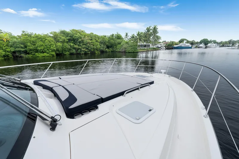  Yacht Photos Pics 2026 Riviera 6000 Sport Yacht on tranquil water with lush greenery backdrop.