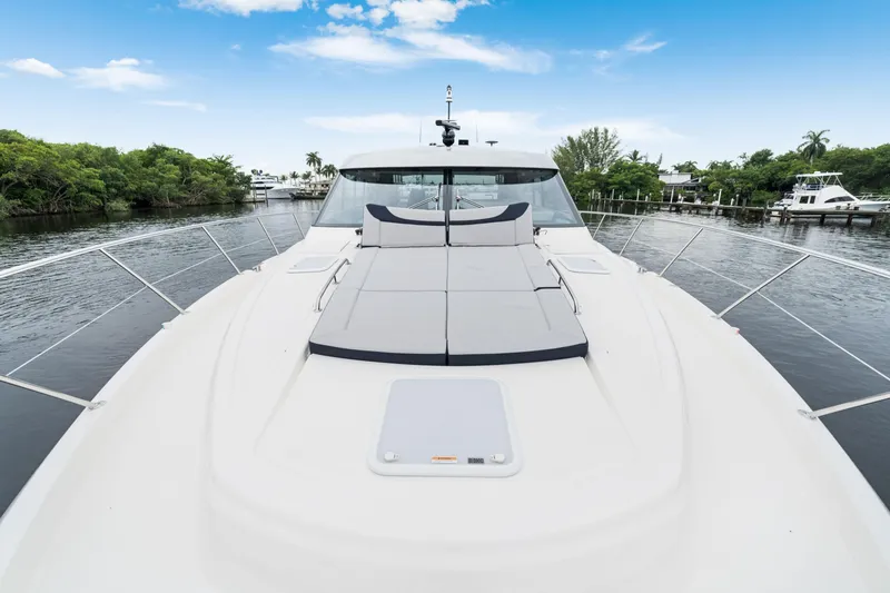  Yacht Photos Pics 2026 Riviera 6000 Sport Yacht on a serene waterway under a clear blue sky.