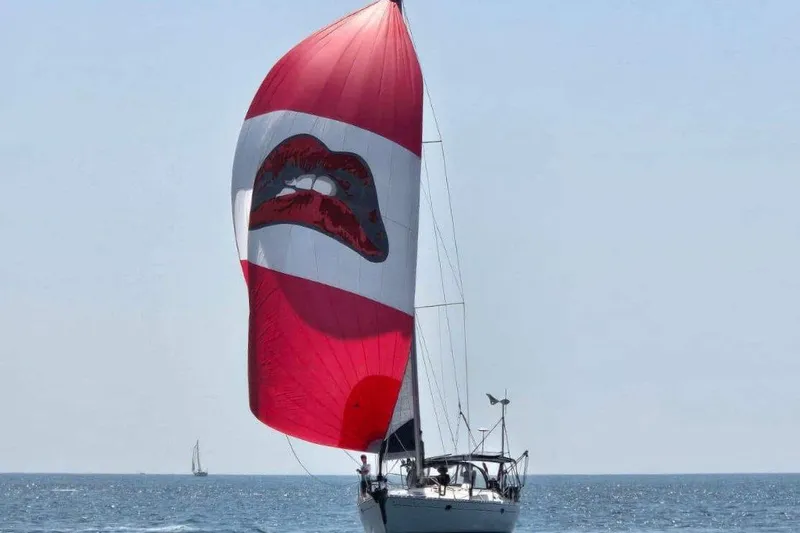 Time Warp Yacht Photos Pics Jeanneau Sun Odyssey 45.2 sailboat with red lips spinnaker on open sea, 2000 model.