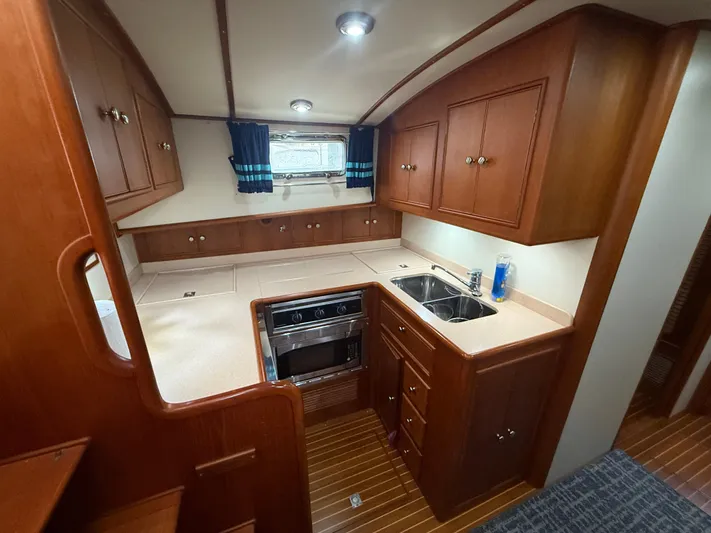 Unconquered Yacht Photos Pics Luxurious 2002 Grand Banks 43 Eastbay HX yacht kitchen with wood cabinetry and modern appliances.