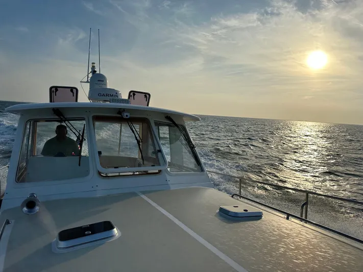 Unconquered Yacht Photos Pics 2002 Grand Banks 43 Eastbay HX cruising at sunset on open sea.
