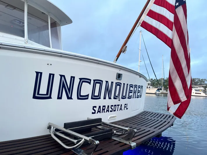 Unconquered Yacht Photos Pics 2002 Grand Banks 43 Eastbay HX boat with American flag, docked in Sarasota, FL.