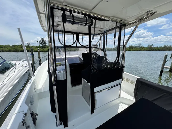  Yacht Photos Pics 2022 Beneteau Flyer 9 SUNdeck boat interior with clear canopy, docked by a scenic waterway.