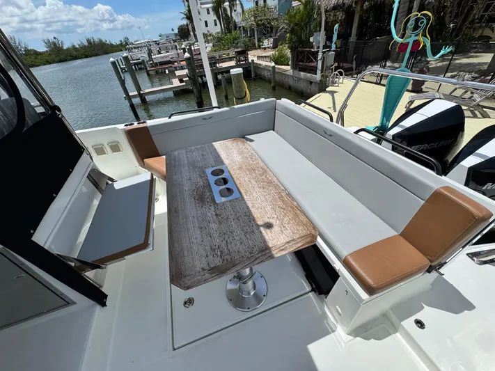  Yacht Photos Pics 2022 Beneteau Flyer 9 SUNdeck boat with spacious seating and wooden table, docked by the water.