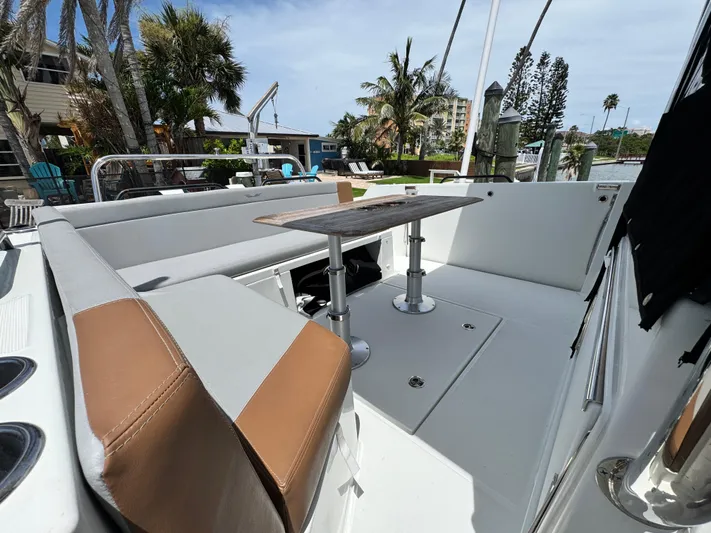  Yacht Photos Pics 2022 Beneteau Flyer 9 SUNdeck boat interior with seating and table, docked near palm trees.