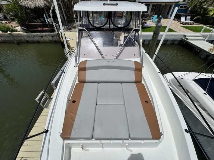  Yacht Photos Pics 2022 Beneteau Flyer 9 SUNdeck boat with cushioned sunbathing area, docked by the water.