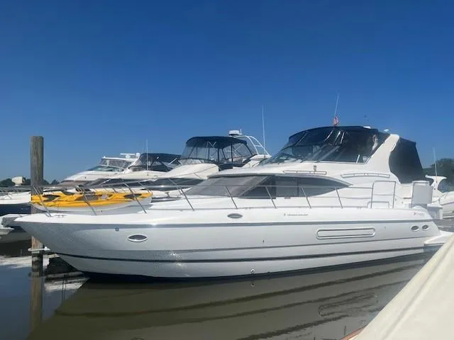  Yacht Photos Pics 2000 Cruisers Yachts 4450 Express Motoryacht docked in a marina under clear blue skies.