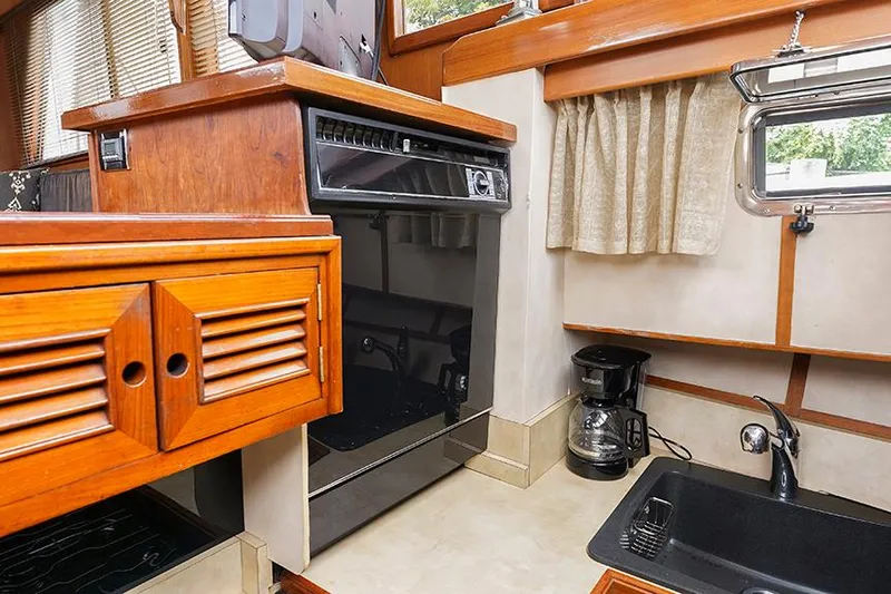 Sunshine Yacht Photos Pics 1986 Marine Trader Tradewinds 47 yacht kitchen with wood cabinetry, oven, coffee maker, and sink.