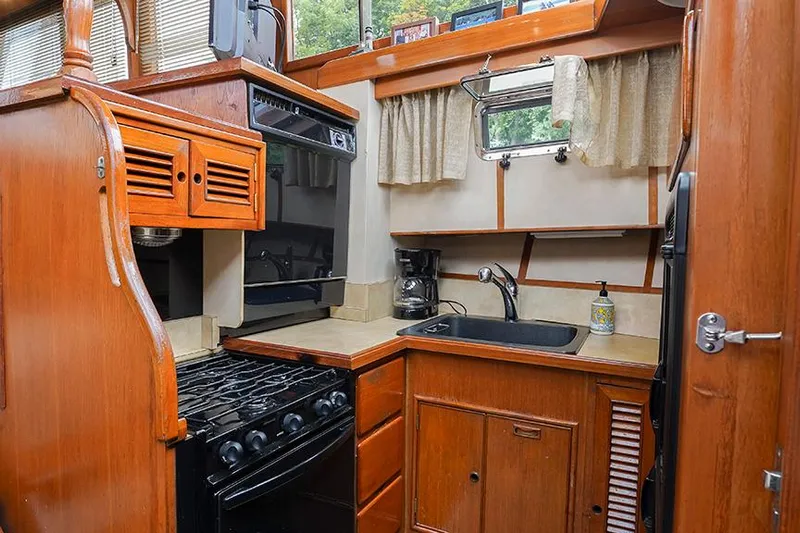 Sunshine Yacht Photos Pics Compact kitchen in 1986 Marine Trader Tradewinds 47 yacht with wood cabinetry and appliances.