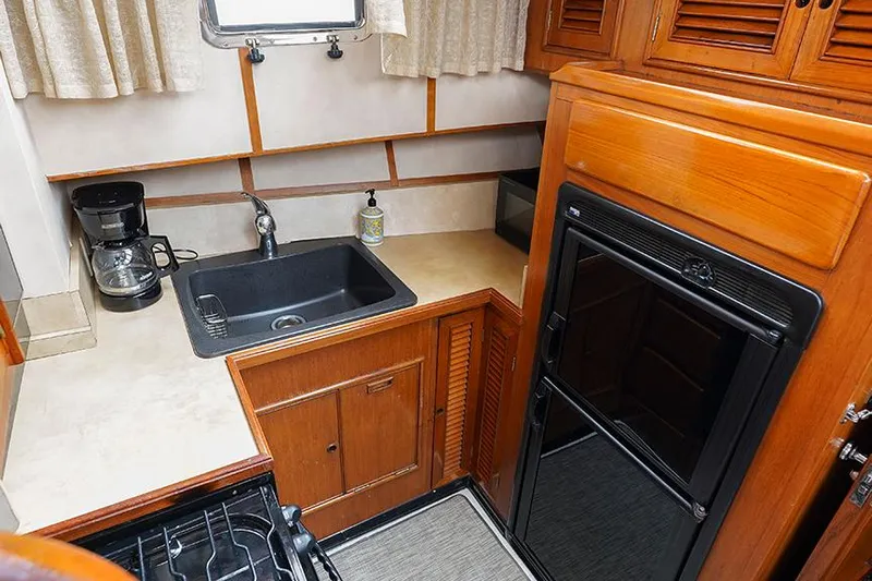 Sunshine Yacht Photos Pics 1986 Marine Trader Tradewinds 47 galley with sink, stove, and wooden cabinetry.