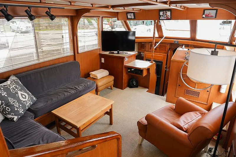 Sunshine Yacht Photos Pics 1986 Marine Trader Tradewinds 47 interior with cozy seating, TV, and wooden accents.