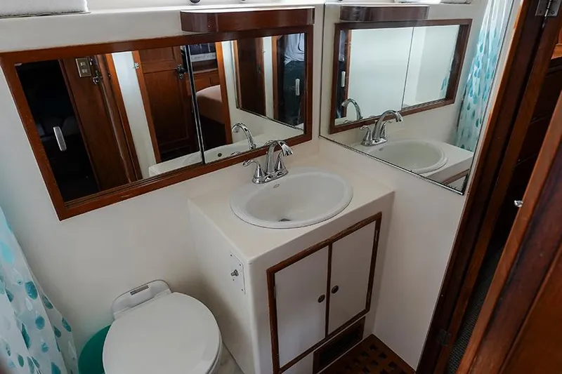 Sunshine Yacht Photos Pics Bathroom interior of 1986 Marine Trader Tradewinds 47 yacht with sink, mirror, and toilet.
