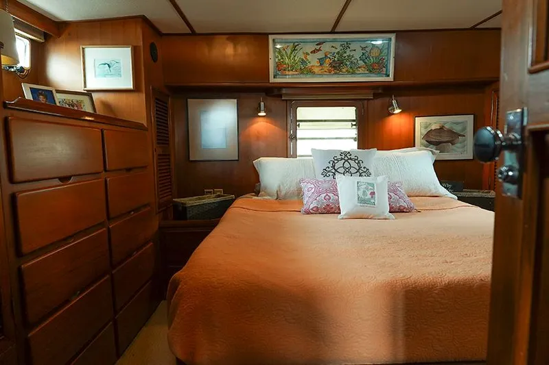 Sunshine Yacht Photos Pics Cozy bedroom in 1986 Marine Trader Tradewinds 47 yacht with wood paneling and decorative art.