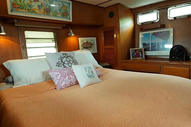 Sunshine Yacht Photos Pics Cozy bedroom in 1986 Marine Trader Tradewinds 47 yacht with decorative pillows and artwork.